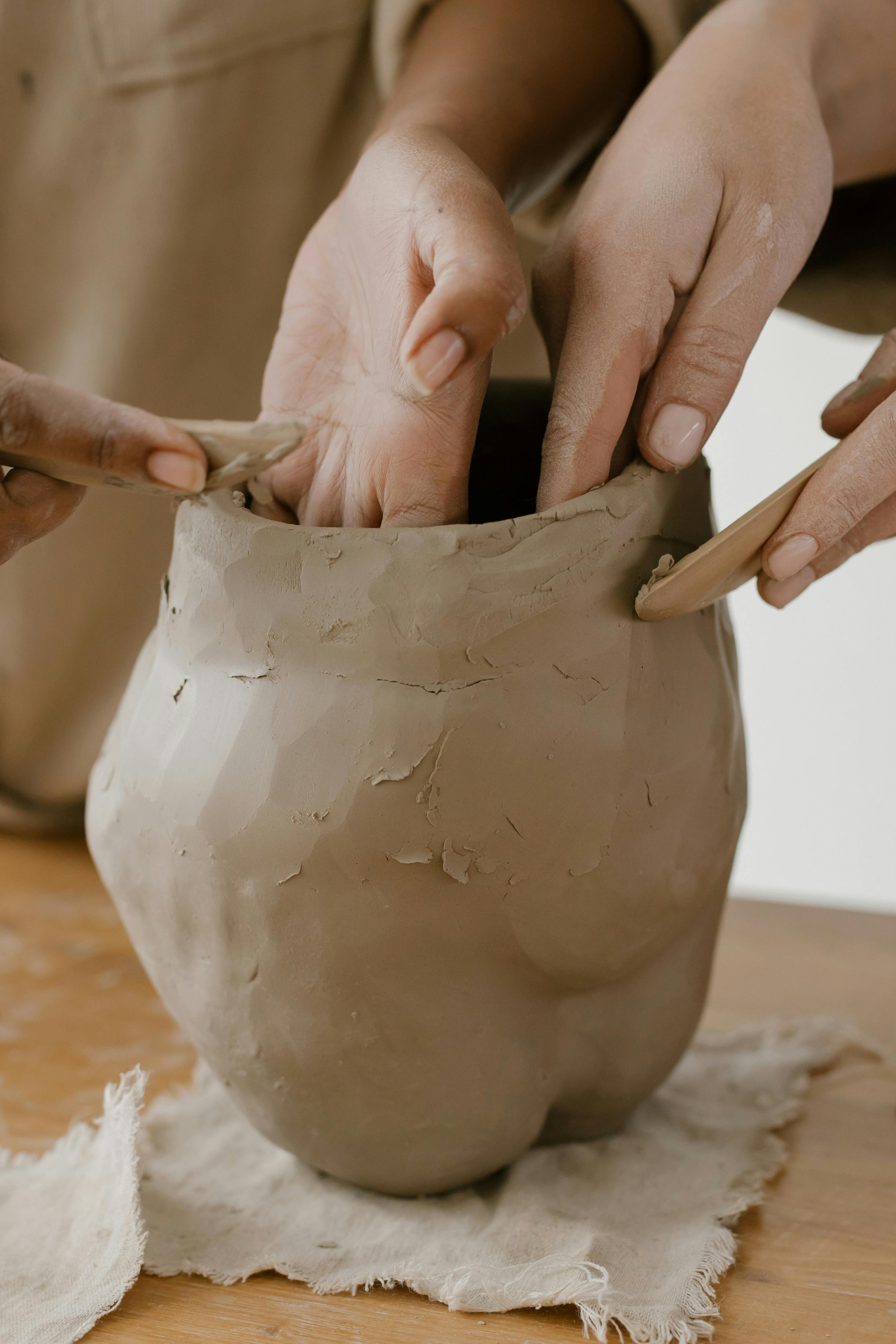 Hands shaping raw material on a work surface.