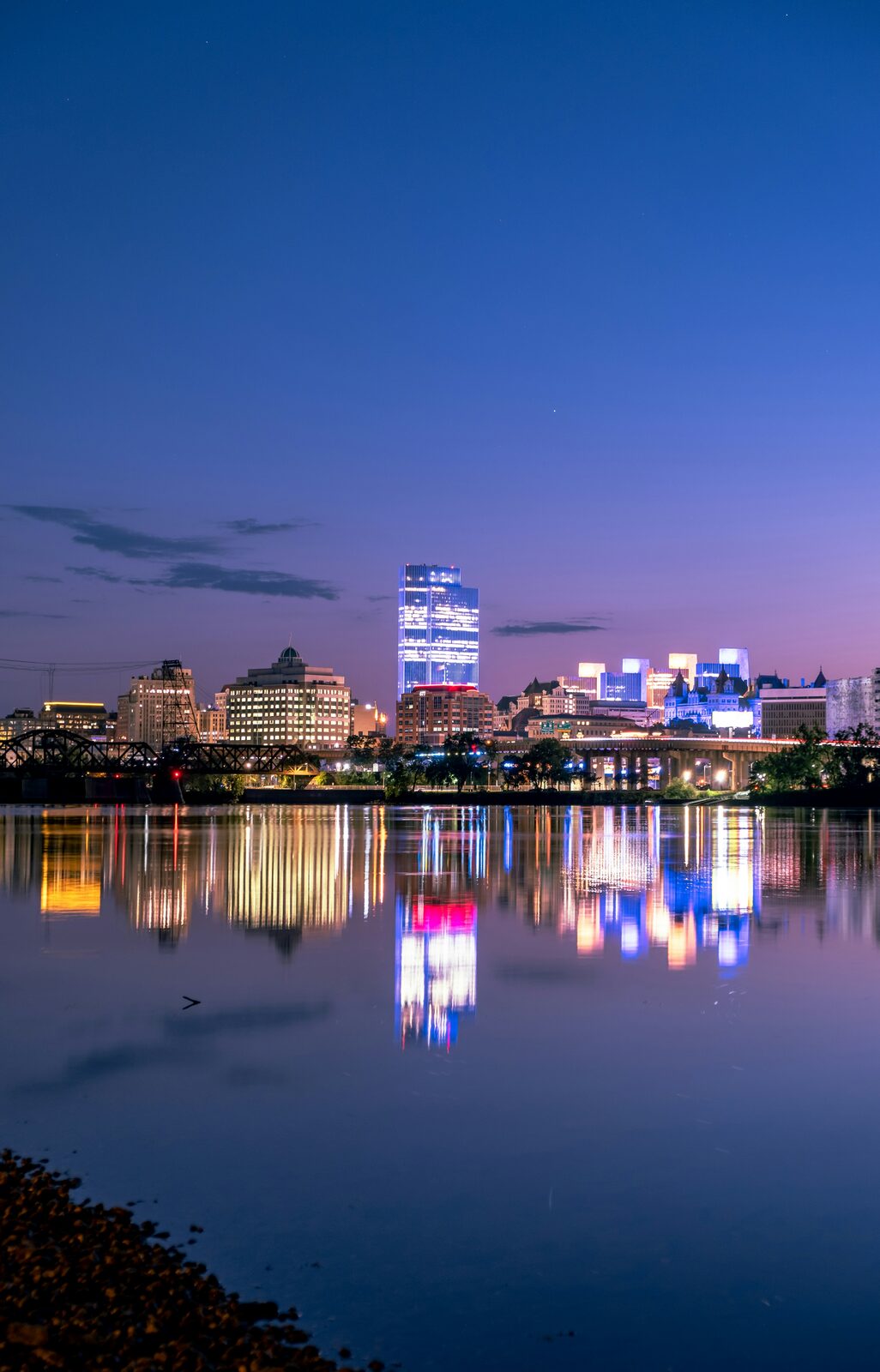 Albany skyline reflected across the Hudson River at night.